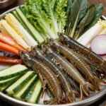 탁자 위에 신선한 알쭈꾸미 샤브샤브와 다양한 채소가 담긲