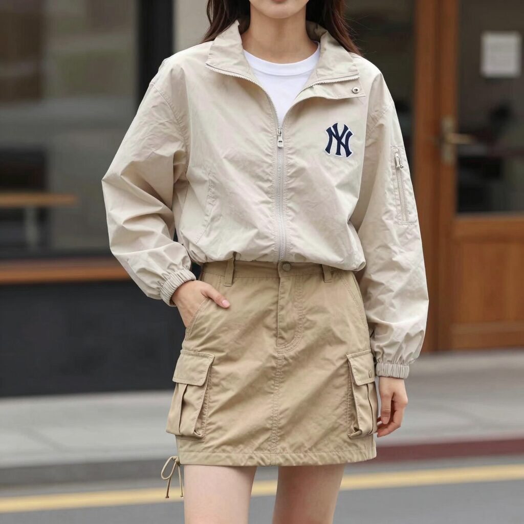 MLB 오버핏 여성 바람막이 점퍼를 입고 카고 스커트와 함께 스타일링한 모습. 밑단 스트링을 조여 핏을 연출했다.