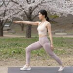 밝은 파스텔 톤의 레깅스를 입고 봄 공원에서 스트레칭하는 여성