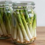 통으로 썬 마늘쫑 장아찌와 채 썬 마늘쫑 장아찌를 각각 유리병에 담은 사진