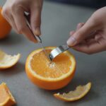 칼과 숟가락을 이용해 오렌지 껍질을 벗기고 있는 과정, 깔끔하게 과육만 분리됨