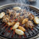 의성 마늘소 덕향 완벽 즐기기 의성 마늘소 덕향의 대표 메뉴인 마늘소 구이가 숯불 위에서 익어가는 모습. 육즙이 맺히고 마늘 조각이 노릇하게 구워져 있다.